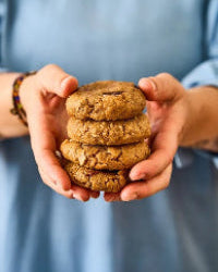 Een stapel koekjes, vastgehouden in handen, tegen een wazige achtergrond.
